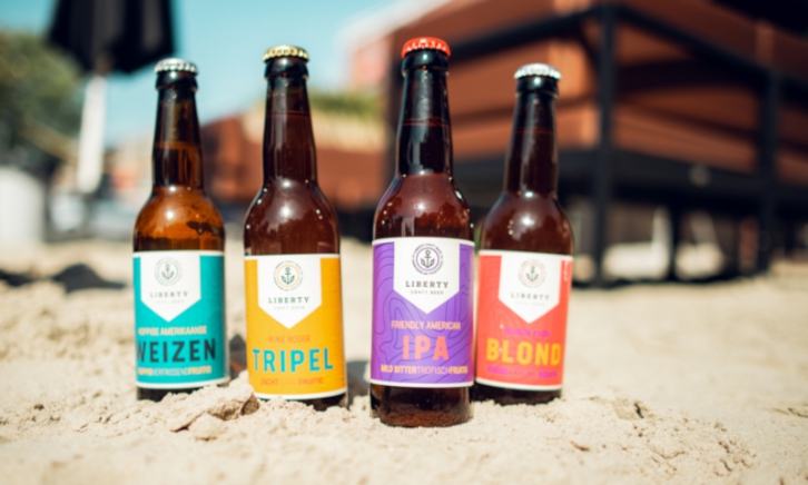 Vier flesjes bier van Liberty Craft Beer in het zand gestoken